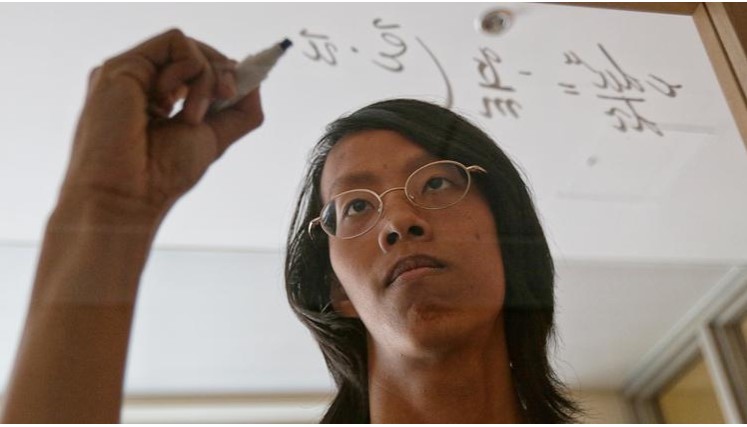 Pheerawich Testimonial A student is writing math formula on the transparent glass board.