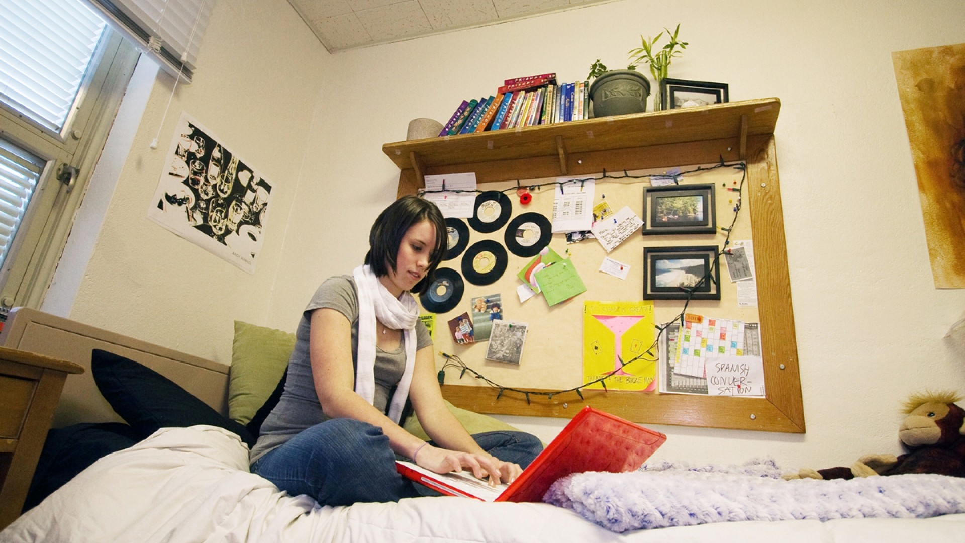 Student studying while sitting on their bed in their residence room located in Lane Hall.