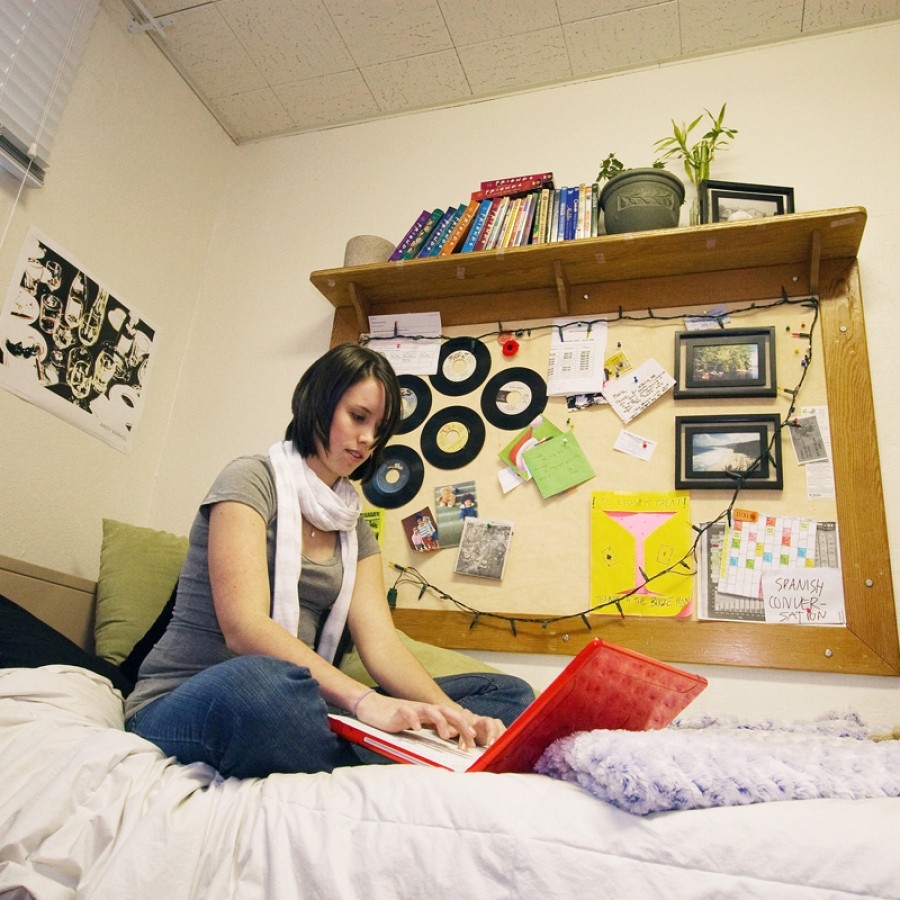 Student studying while sitting on their bed in their residence room located in Lane Hall.
