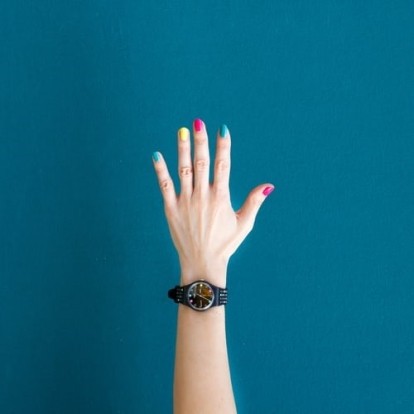 Human hand on blue background with colorful nails
