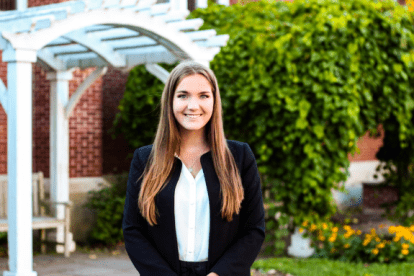 Smiling person dressed smartly standing in front of building